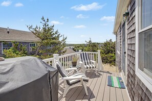 Une terrasse couverte avec deux fauteuils Adirondack, une petite table et une plante en pot.