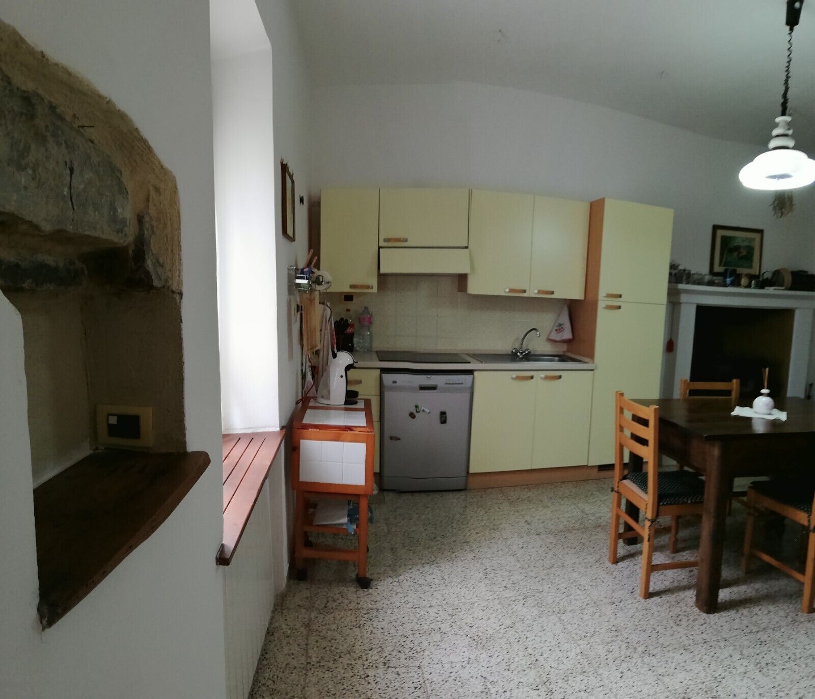 A compact kitchen with a dishwasher, a sink, and a dining area with a table and chairs.