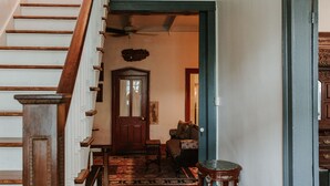 Una scala in legno conduce a una stanza con un tappeto decorato, una porta in legno e un piccolo tavolo.