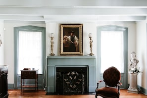 A room with a fireplace, a painting, and a bust statue.