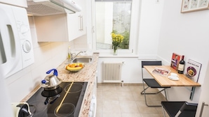 A compact kitchen with a stove, sink, and a dining area with a table and chairs.
