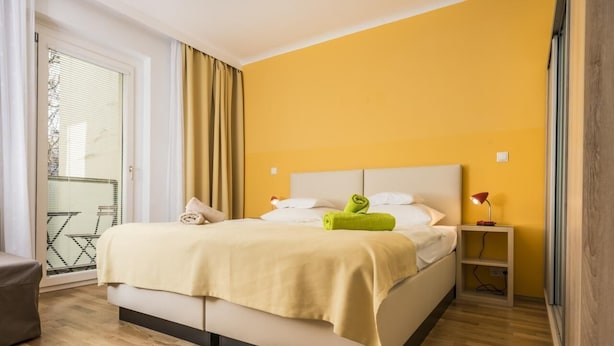 A modern hotel room with a large bed, a small bedside table, and a view of a balcony.