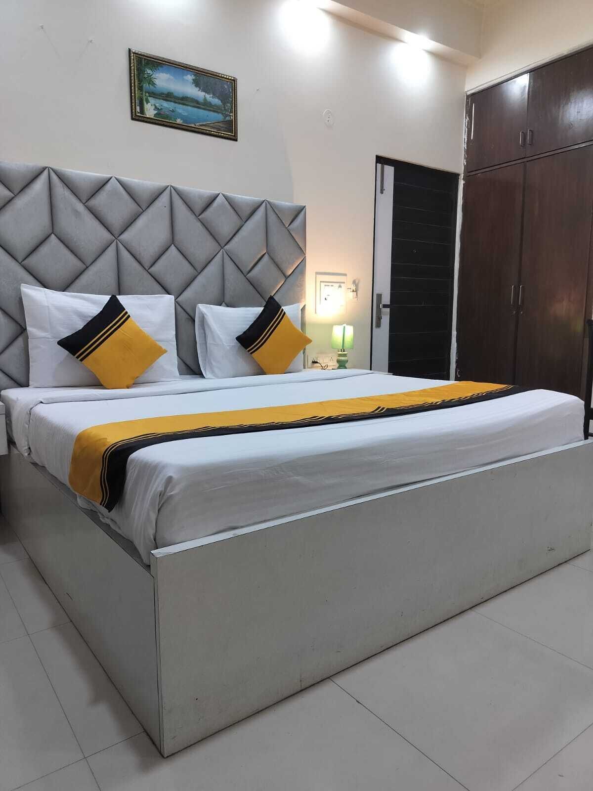 A bedroom with a bed, a headboard, a wardrobe, and a painting on the wall.