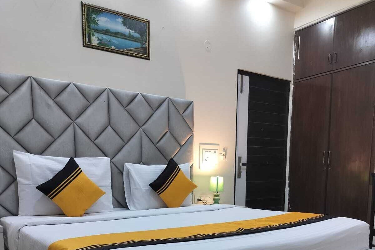 A bedroom with a bed, a headboard, a wardrobe, and a painting on the wall.