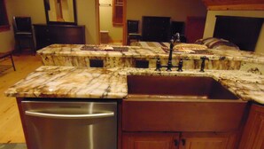 A kitchen with a stainless steel dishwasher, wooden cabinets, and a marble countertop. - Upscale Apt Available for short/ long stays. Kitchen, bath, laundry w/ Generator (Eatonton)
