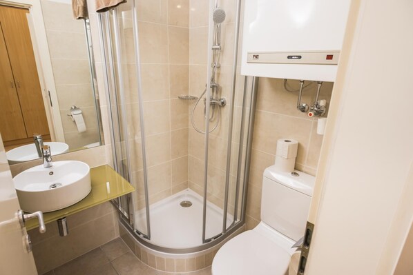 A modern bathroom with a glass-enclosed shower, a sink, and a toilet.