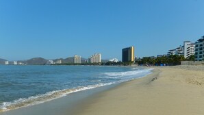 Una playa con vista despejada al océano y un paisaje urbano al fondo.