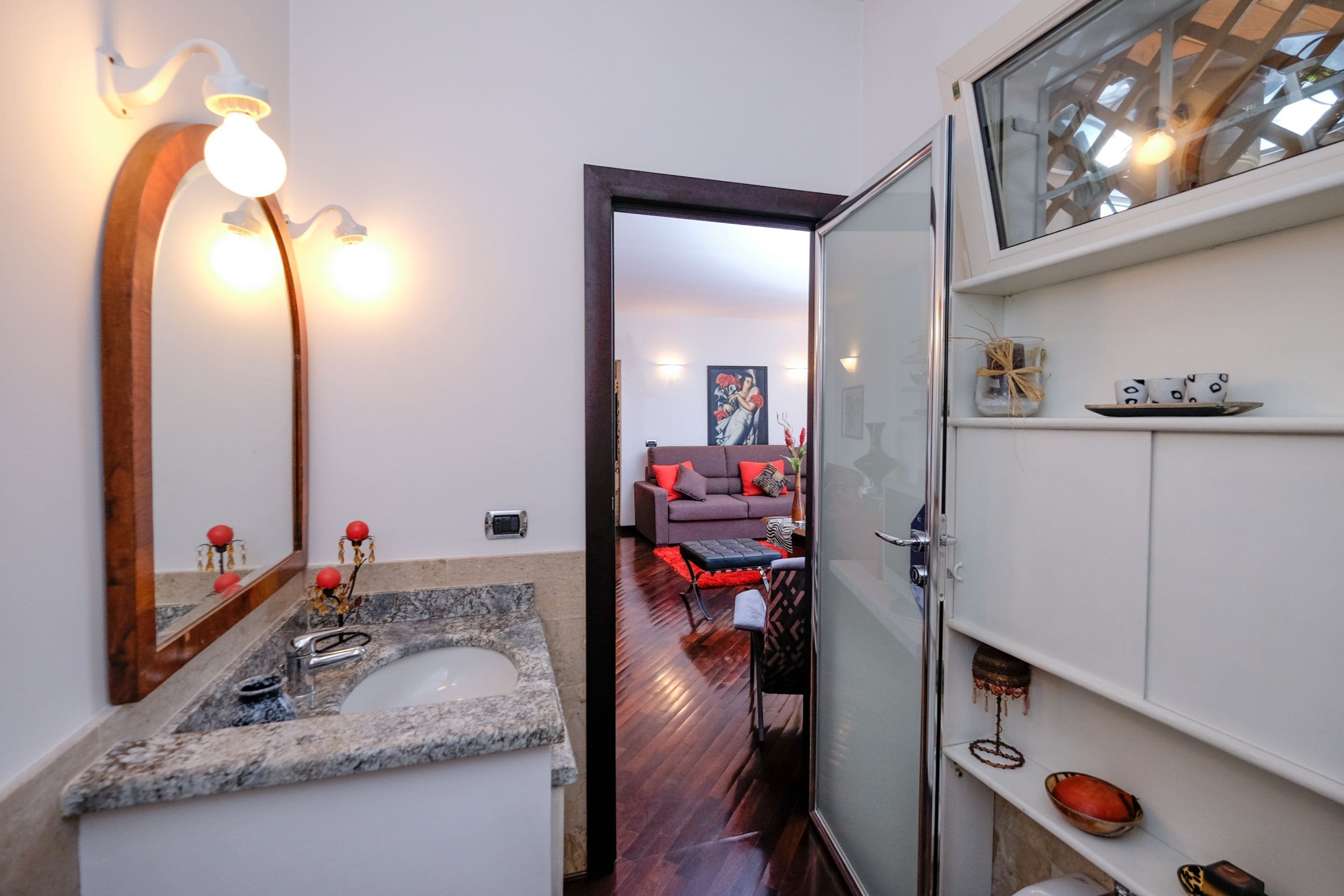 Un baño moderno con un lavabo de mármol, un espejo grande y una cabina de ducha de vidrio.