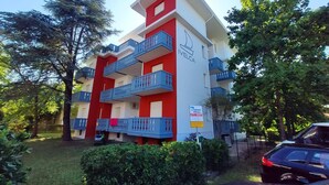 Un immeuble à plusieurs étages doté de balcons, une enseigne indiquant qu’il s’agit d’un hôtel, et une voiture garée devant.