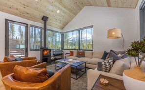 Ein modernes Wohnzimmer mit Ledersofas, einem Holztisch und einem großen Fenster mit Blick auf die Berge.