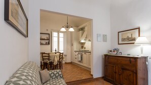 Una sala de estar con un sofá estampado, un aparador de madera y un comedor con mesa y sillas.