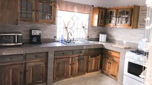 A kitchen with wooden cabinets, a microwave, a coffee maker, and a stove. - YD Rooftop Lounge ocean view salt water pool with mountain view large 2bdrm  (Montego Bay)