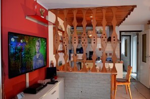 Cozinha moderna com divisória de madeira, televisão na parede e área de jantar com uma cadeira.