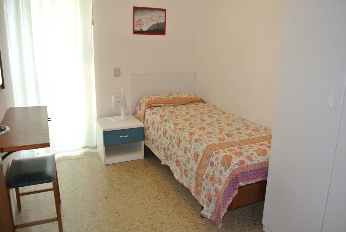 Een slaapkamer met een bed, een bureau en een stoel.