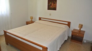 Ein Schlafzimmer mit einem Holzbett, einem Nachttisch mit Lampe und einem an der Wand hängenden Gemälde.
