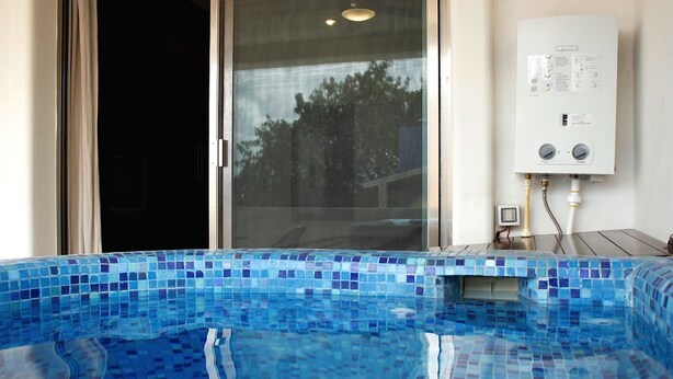 A swimming pool with blue mosaic tiles, a sliding glass door, and a water heater unit on the wall. - Kingsize 1bdr apt w/private balcony&jacuzzi, common rooftop w/pool (unit104) (Playa del Carmen)