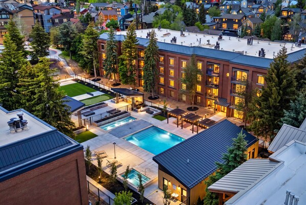 A residential building with a swimming pool, outdoor seating, and a well-maintained lawn.