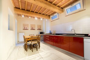 Una cocina moderna con armarios rojos, una mesa de comedor de madera y un salpicadero de azulejos.