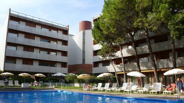Un hôtel doté d’une piscine, d’un espace extérieur aménagé et d’un bâtiment à plusieurs étages avec des balcons.