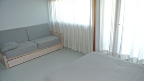 Une chambre à coucher avec un lit, un canapé et une fenêtre avec des rideaux.