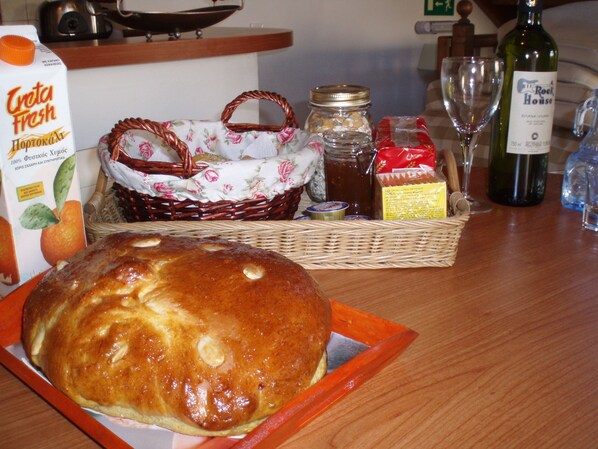 A loaf of bread on a tray, a bottle of wine, a jar of honey, and a basket with a cloth.