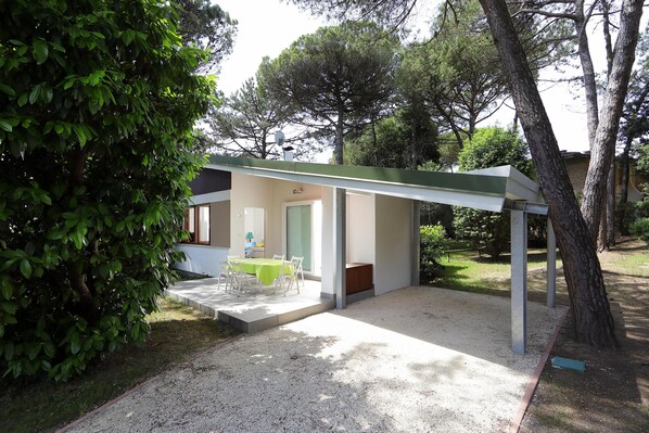 Un espace extérieur moderne aménagé avec une table et des chaises, un patio couvert et un chemin de gravier.