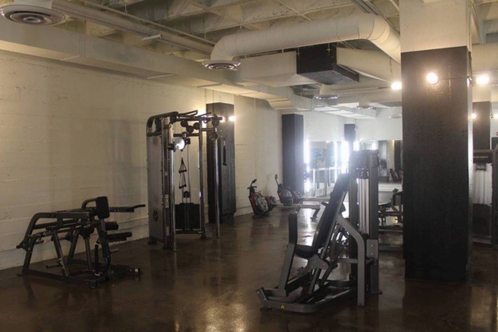 A gym with various exercise equipment, including weight machines and a treadmill.