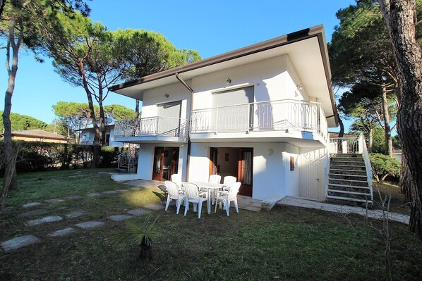 Un bâtiment à deux étages doté d’un balcon, d’un escalier et d’un patio aménagé avec des chaises.
