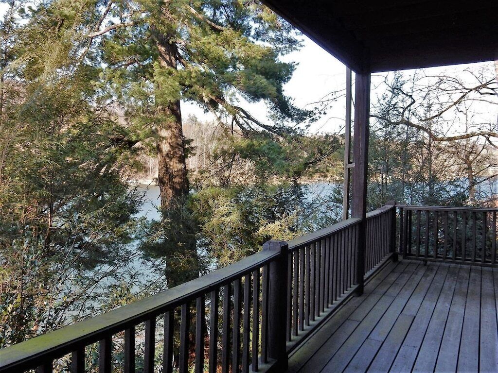 A wooden deck with a railing overlooking a body of water and trees.