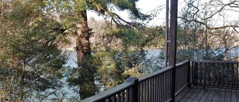 A wooden deck with a railing overlooking a body of water and trees.