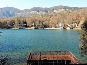 Una propiedad frente al lago con un muelle de madera, vista al lago y casas al fondo.