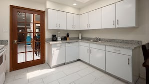 A modern kitchen with white cabinets, a granite countertop, and a skylight above the sink. - Vista Verde 102, Cozy Condo in Brownsville (Brownsville)