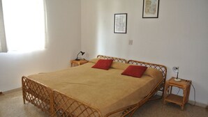 Une chambre à coucher avec un lit, deux tables de chevet, une fen être et deux tableaux encadrés accrochés au mur.