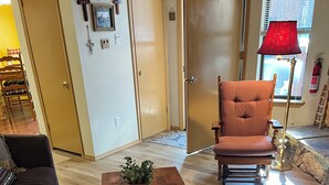 Uma sala de estar acolhedora com uma mesa de centro de madeira, um sofá escuro e uma poltrona estofada.