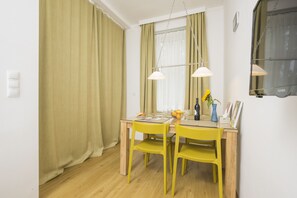 Un coin repas avec une table en bois, des chaises jaunes et deux lampes suspendues.