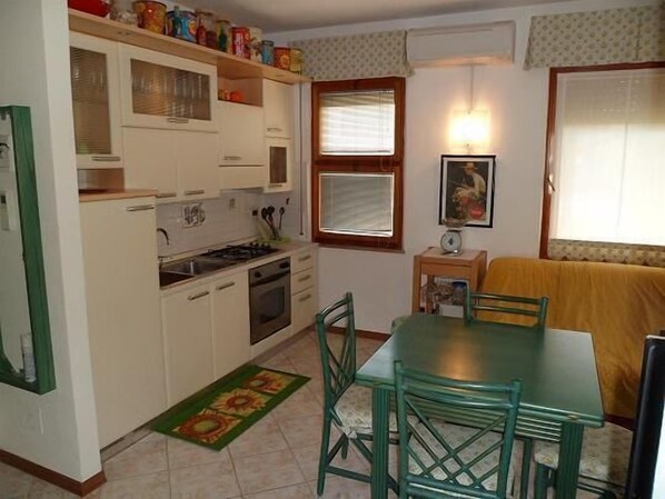 Une cuisine de taille réduite avec des meubles blancs, une cuisinière et une table à manger avec des chaises.
