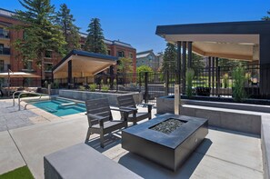 A pool area with a hot tub, seating, and a covered patio.