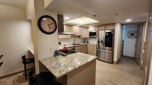 A modern kitchen with granite countertops, stainless steel appliances, and a wall clock. - Main St/Town Lift/Hot Tub/Parking (Park City)