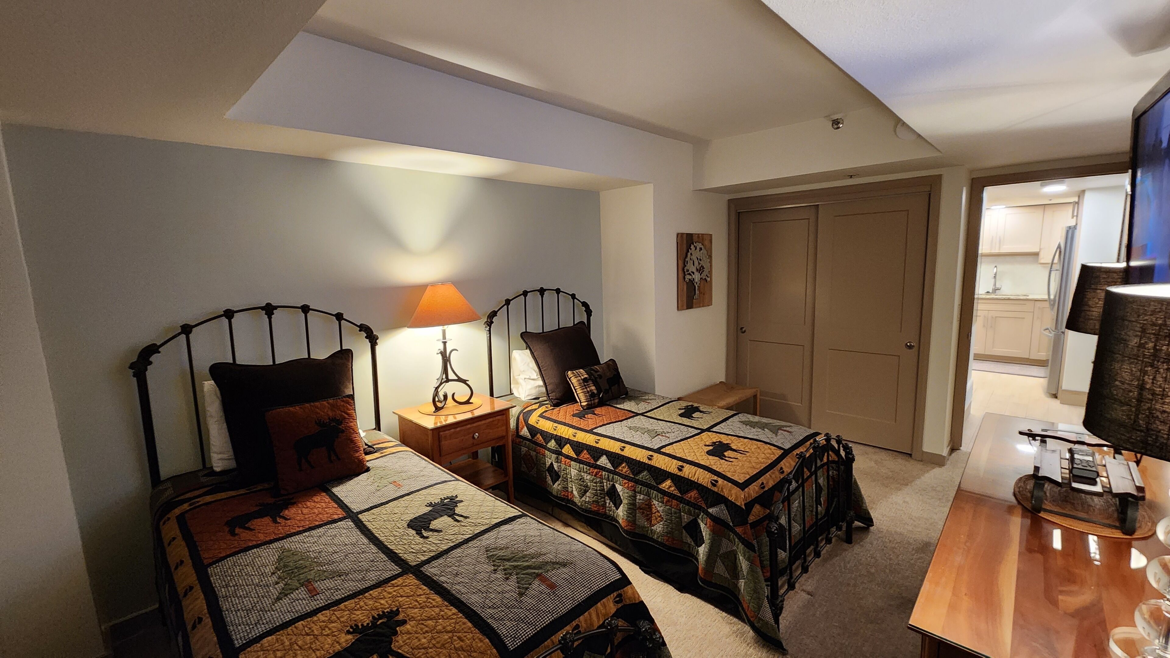 Ein Schlafzimmer mit zwei Betten, einem Nachttisch mit Lampe, einer Holzkommode und einer Tür zu einem Badezimmer.