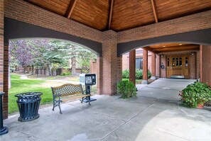 Relax in a serene outdoor space surrounded by lush greenery and a brick structure with wooden beams.