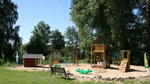A playground with swings, a slide, and a small shed.