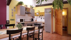 A compact kitchen with a dining area, featuring a wooden table, chairs, and a refrigerator.