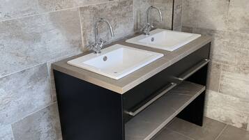 A modern bathroom with two sinks, a black vanity, and a mirror above the sinks.