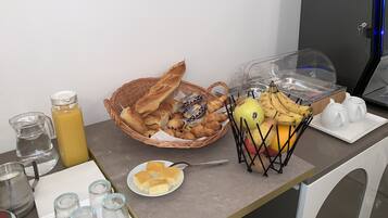 Una mesa con pan, pasteles, frutas y salsas para el desayuno.