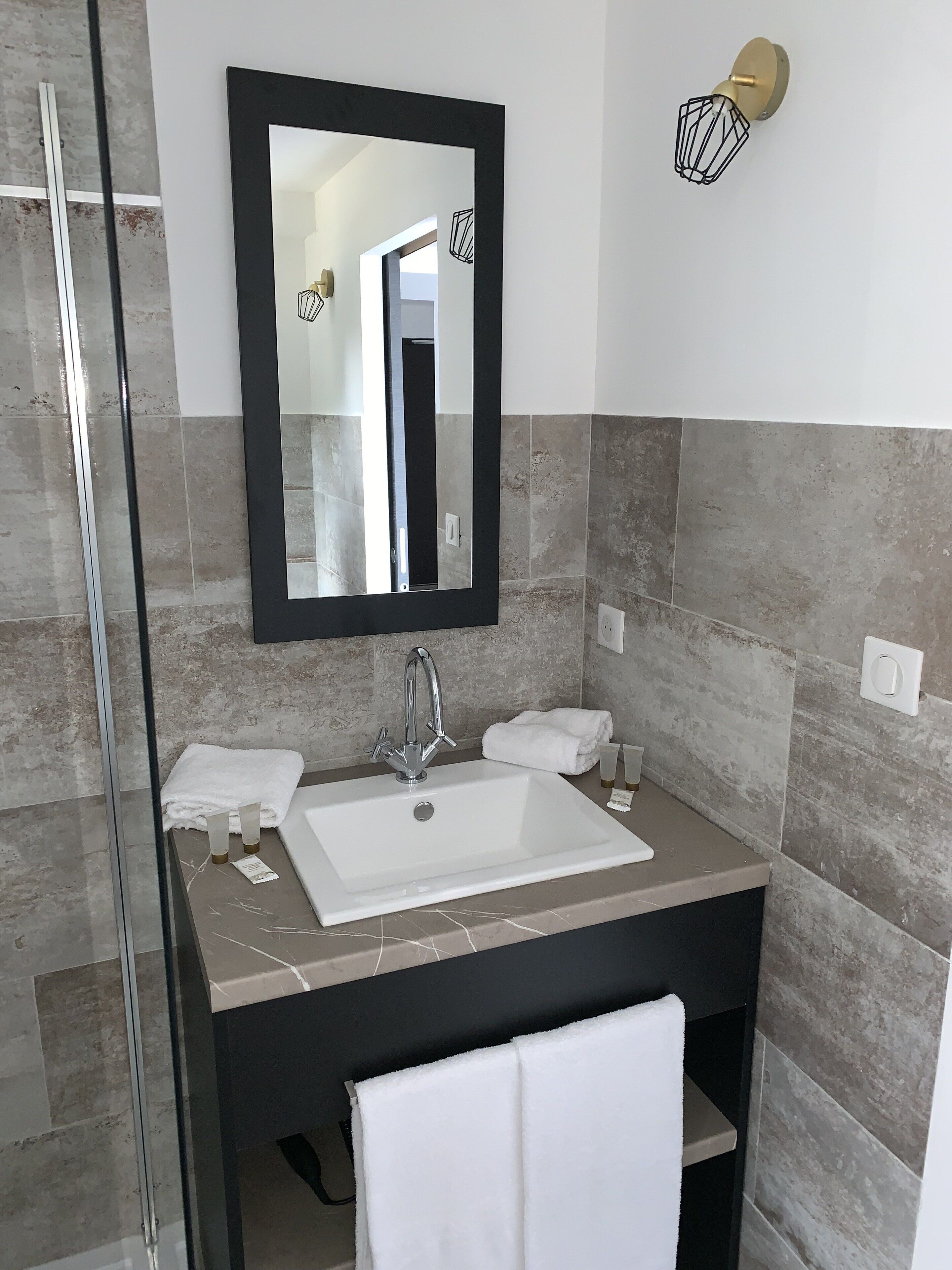 A modern bathroom with a large mirror, a white sink, and a black vanity.
