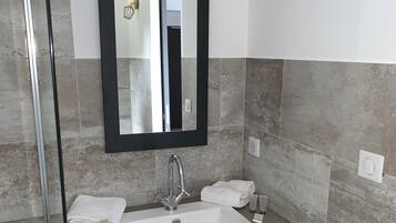 A modern bathroom with a large mirror, a white sink, and a black vanity.
