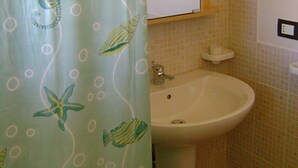 A bathroom with a sink, a mirror, and a shower curtain with sea creature designs. - Villa Flavia, holiday home in Noto (Noto)