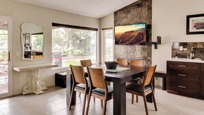 Un comedor moderno con una mesa grande, sillas, una consola decorativa y una pared de piedra decorativa.