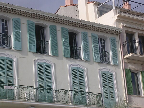 A building with multiple windows and balconies, featuring green shutters and wrought iron railings. - 3 rooms, 91 m2, sea front, for 6 people, classified 3 * (Cannes)