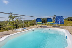 A swimming pool with two lounge chairs and a covered area.